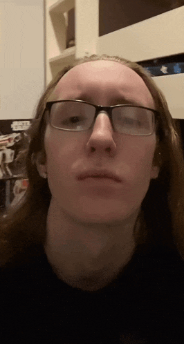 a man with long hair and glasses is making a funny face