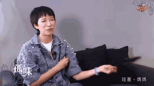 a woman in a denim jacket sits on a couch