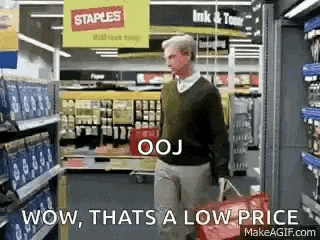 a man is walking down a aisle in a store carrying a shopping bag .