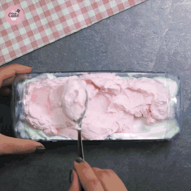 a person is scooping ice cream out of a plastic container that says cake on the bottom