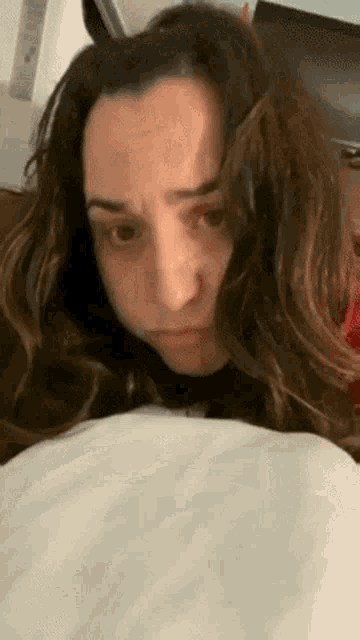 a woman with long hair is laying on a bed with her head on a pillow .