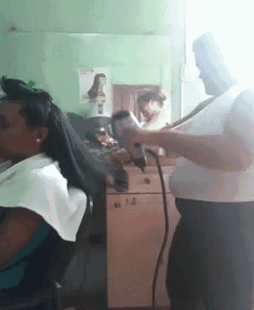 a woman getting her hair blow dried by a man