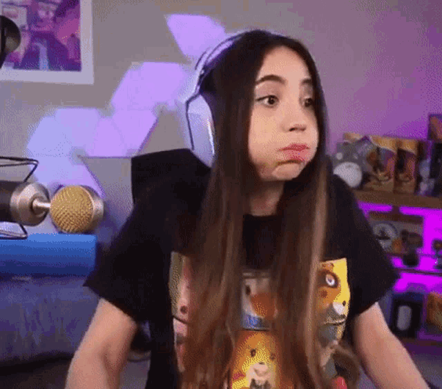 a girl wearing headphones and a t-shirt is making a funny face .