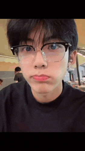the boy is wearing glasses and making a funny face .