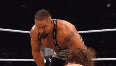 two men are wrestling in a ring and one of them is wearing a belt .