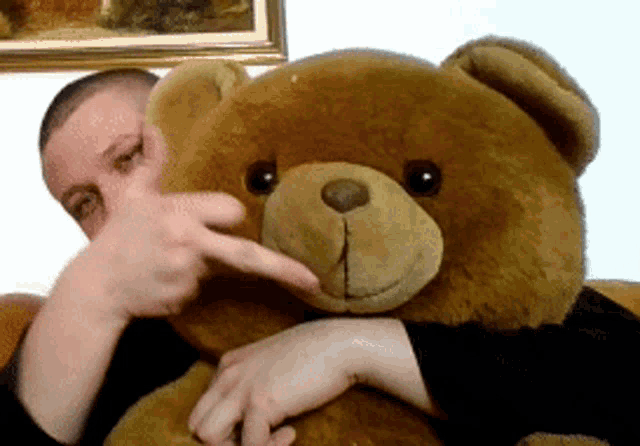a man is holding a teddy bear and pointing to it