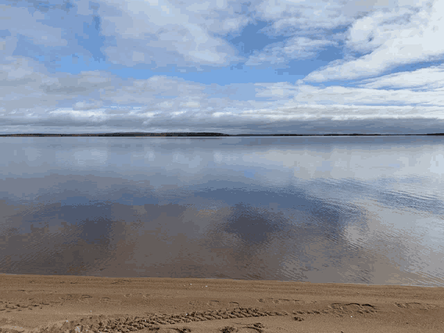 a large body of water with a blue sky and clouds in the background