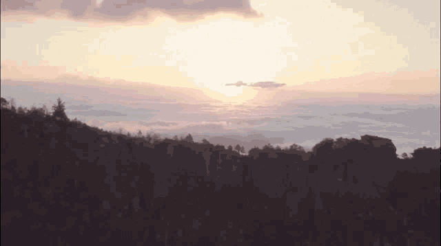 the sun is setting over the clouds in the valley