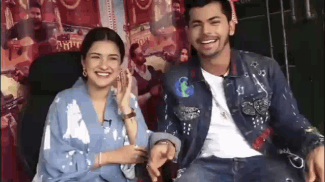 a man and a woman are laughing together while sitting next to each other .
