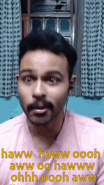 a man with a mustache is wearing ear buds and making a funny face .