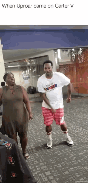 a man wearing a tommy hilfiger shirt is dancing in front of a woman