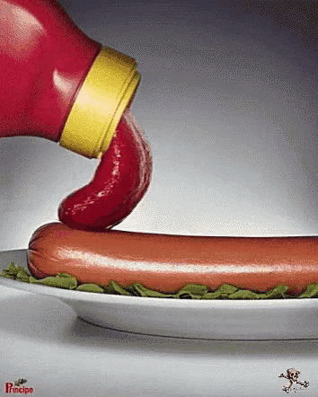 a hot dog on a plate with ketchup being poured on it