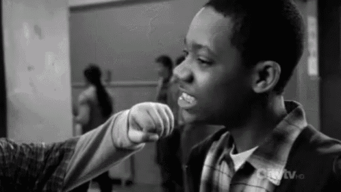 a black and white photo of a boy pointing at another boy .