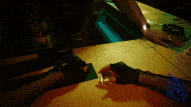 a woman in fishnet stockings sits at a table with a lighter