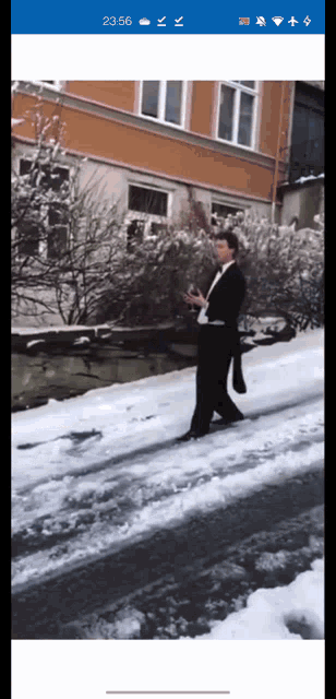 a man in a tuxedo walking down a snowy street