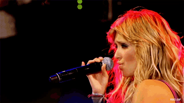 a woman singing into a microphone with a rbd.gif watermark