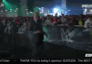 a man in a suit is standing in front of a wwe sign