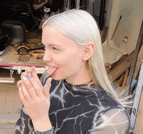 a woman with white hair is licking her fingers