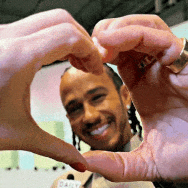 a man and a woman are making a heart with their hands