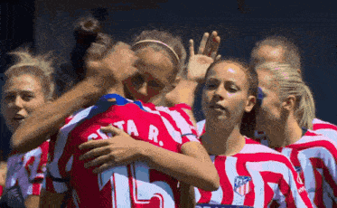 a group of female soccer players are hugging and one of them has the number 15 on her jersey