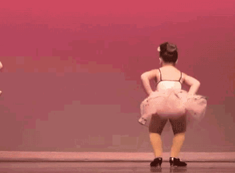 a little girl is dancing in front of a sign that says " what you want "