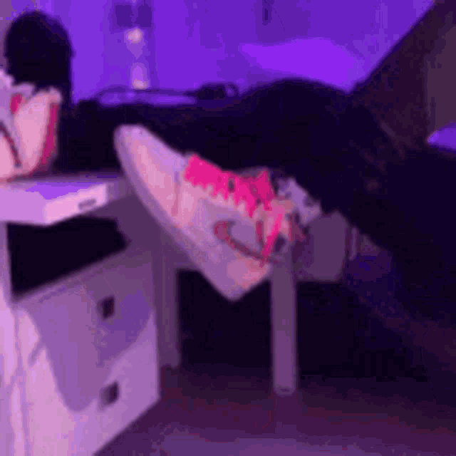 a person laying on a bed with their feet up on a nightstand .
