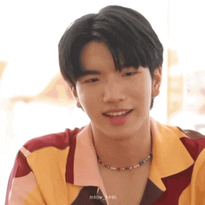 a close up of a young man wearing a yellow shirt and a necklace .