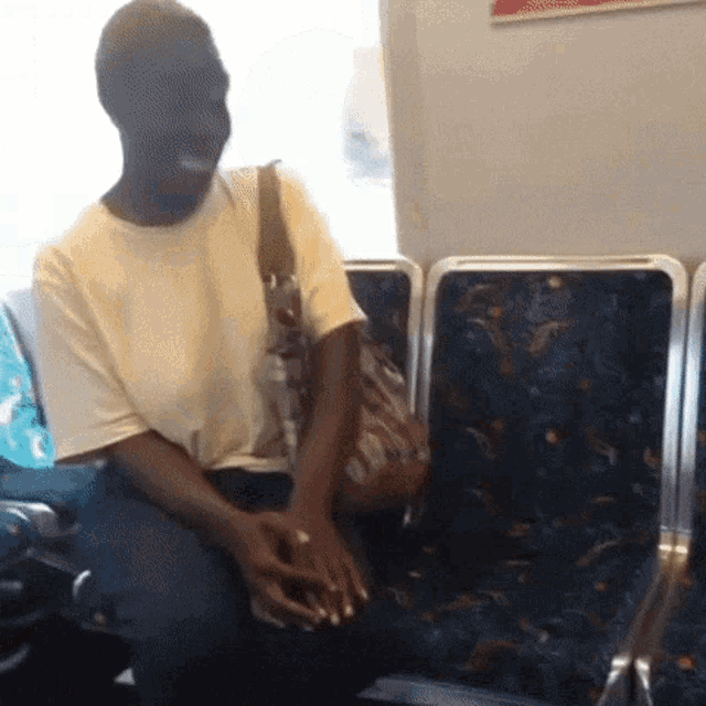 a man in a yellow shirt is sitting on a bus with his hands folded