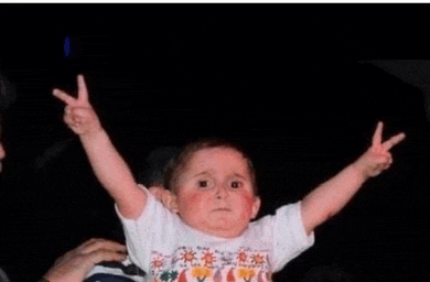 a baby is giving the peace sign with his arms in the air .