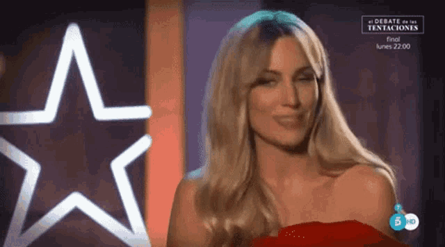 a woman in a red dress is smiling in front of a star and the words el debate de las tentaciones