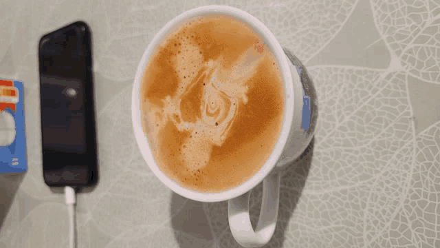 a cup of coffee next to a phone and a card that says mastercard