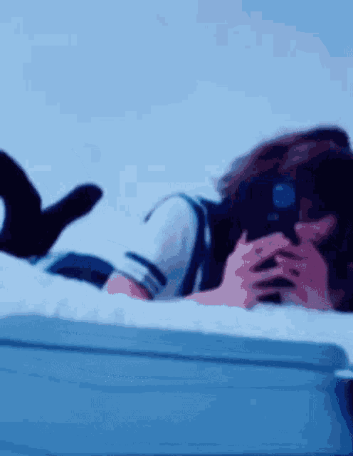 a woman is laying on her stomach on a bed looking at her phone .