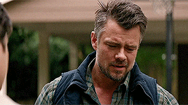 a man with a beard wearing a plaid shirt and a vest is standing next to another man .