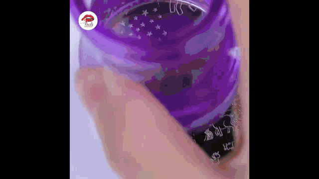 a close up of a person holding a purple glass with a purple liquid in it .