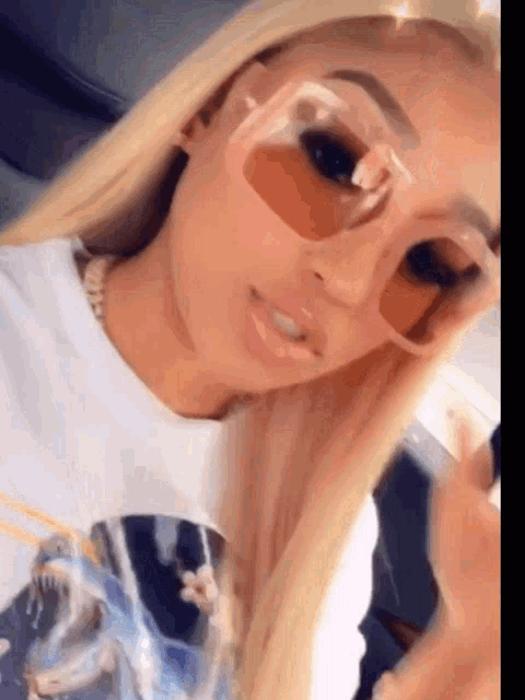 a close up of a woman wearing sunglasses and a white shirt