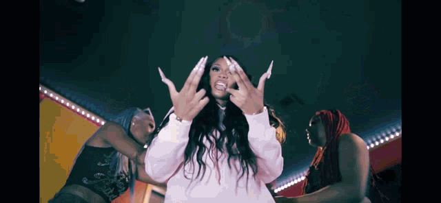 a woman in a white sweatshirt is making a hand gesture while dancing with two other women .