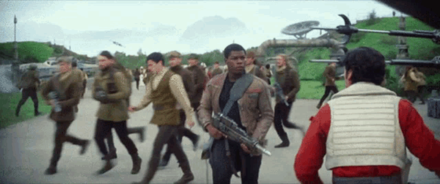 a man in a red jacket is holding a gun in front of a crowd of men