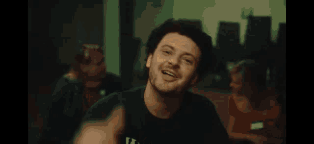a man wearing a green shirt with the letter t on it is smiling