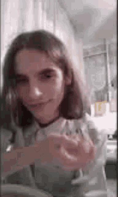 a young man with long hair is smiling and holding a piece of paper in his hand .