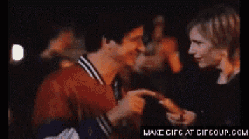 a man and a woman are dancing in a dark room with the words make gifs at gifsoup.com below them .