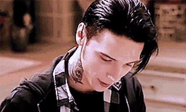 a young man with a tattoo on his neck is wearing a black shirt and a black jacket .