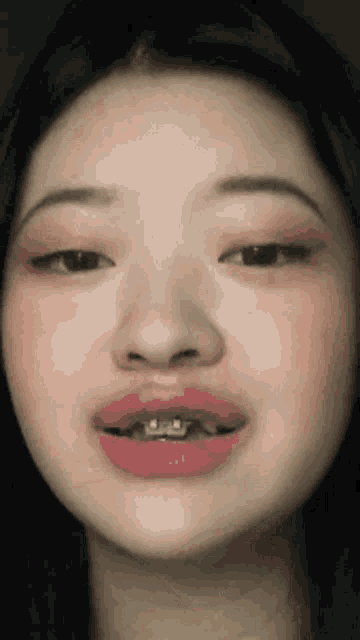 a close up of a woman 's face with braces and pink lips