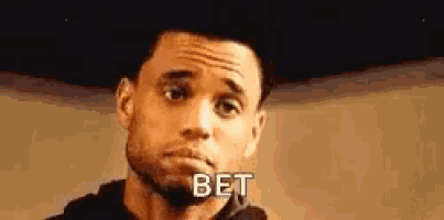 a man with a beard is making a funny face and the word bet is written on his face .