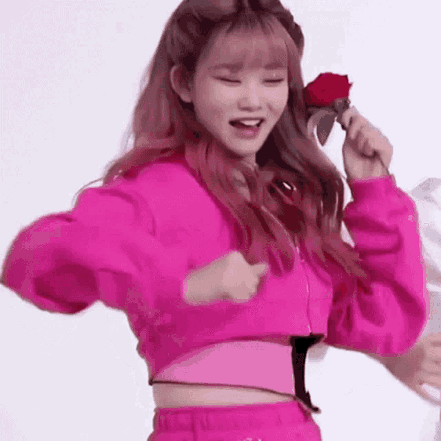 a woman in a pink jacket is holding a red rose and dancing .
