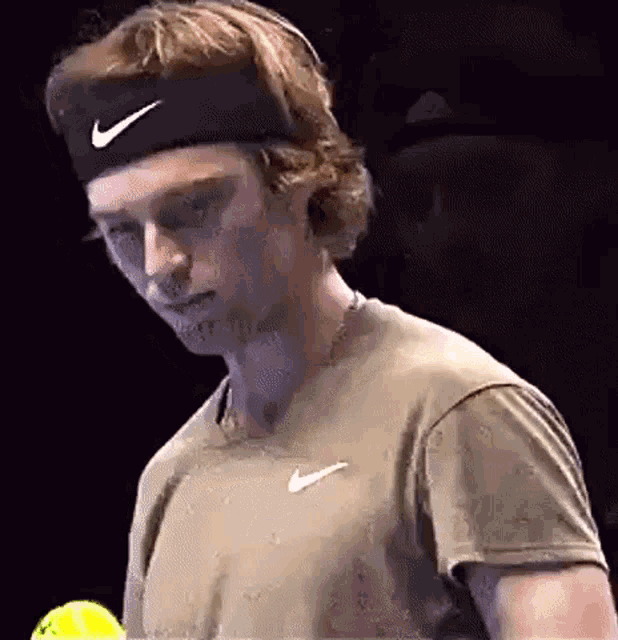 a tennis player wearing a nike headband is holding a tennis ball .