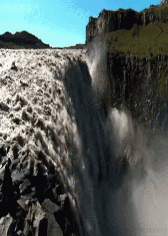 a large waterfall is surrounded by rocks and mountains