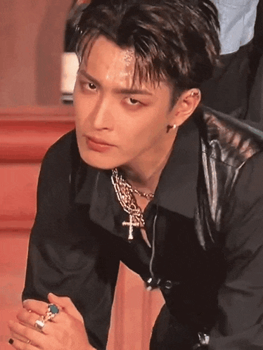 a close up of a person wearing a black shirt and a cross necklace