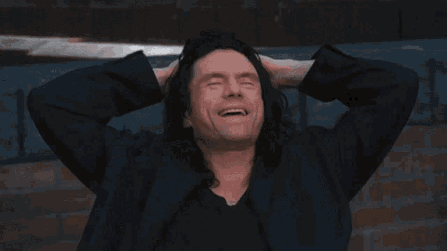 a man with long hair is smiling and says what