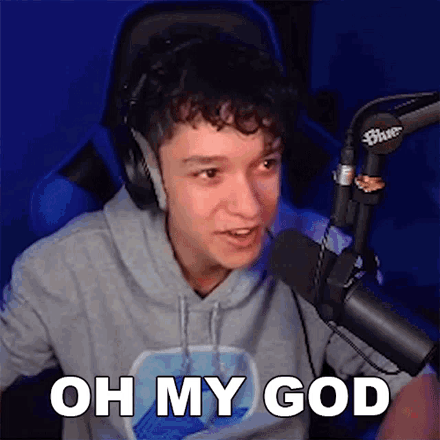 a man wearing headphones is sitting in front of a microphone and says oh my god