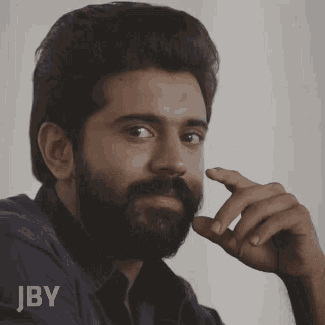 a man with a beard has jby written on the bottom of his shirt